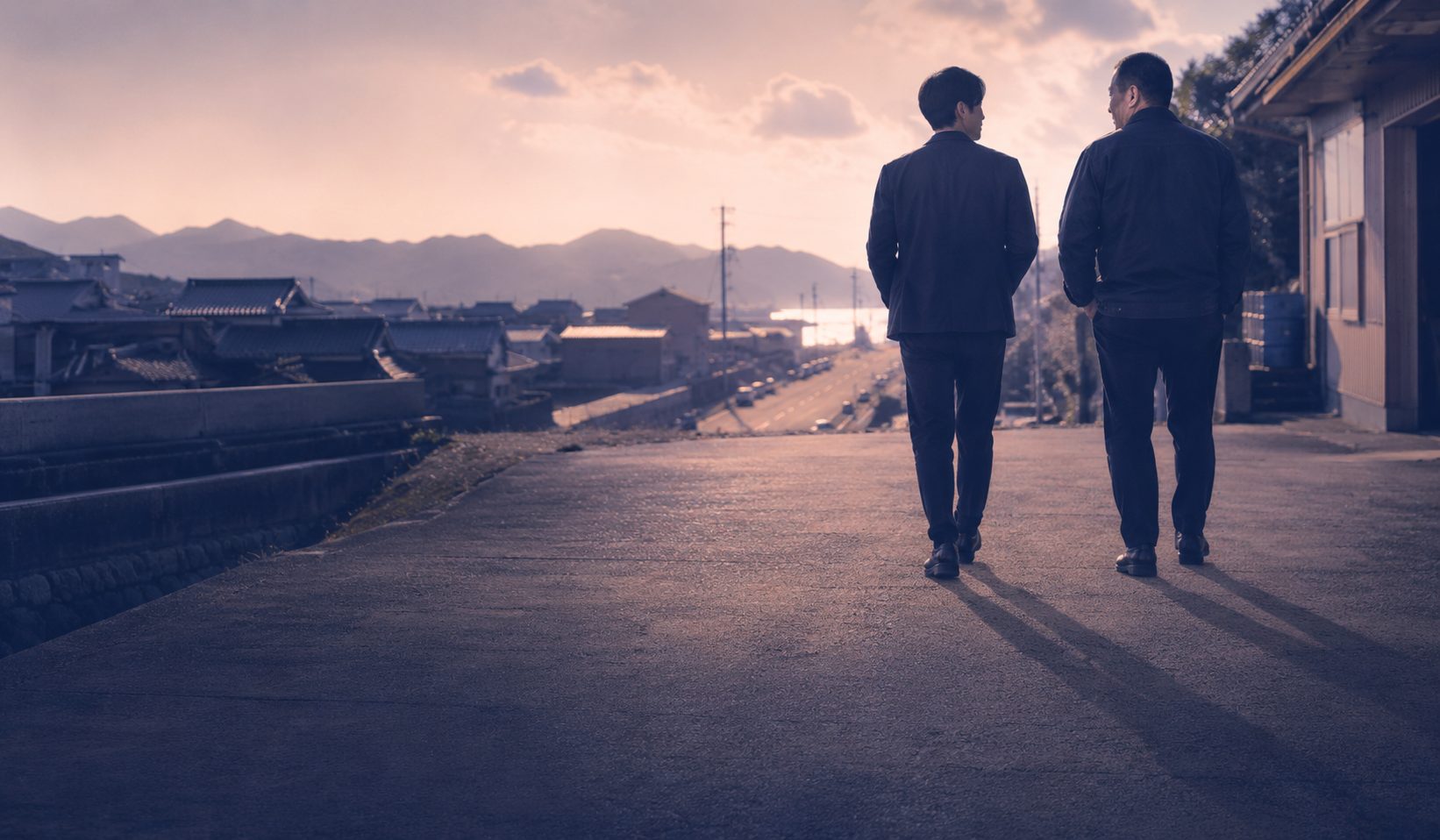 地方の道を前を向いて並んで歩く2人